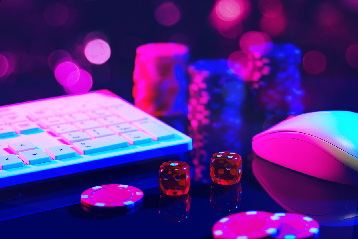 Red Dice on a Pink Surface With a Computer Keyboard and Mouse